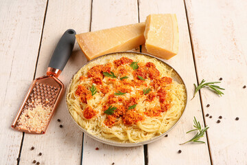 Plate of tasty Italian pasta with Parmesan cheese on light wooden background
