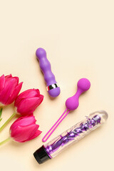 Sex toys with tulips on beige background