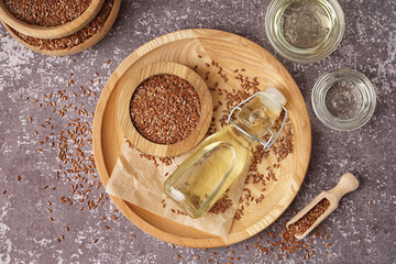 Bottle with flax oil and seeds on grey grunge background