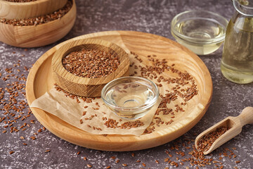 Bowl with flax oil and seeds on grey grunge background