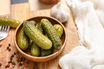 Bowl with tasty fermented cucumbers on beige background