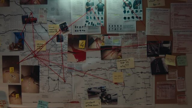 Crime scene photos, newspaper articles, mugshots, maps, notes, fingerprints and evidence connected with red thread pinned to a board on the wall in the detective office. No people, night time