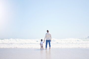 Father, son and beach with back, space and mock up with blue sky, lens flare and bonding with love in summer. Papa, male kid and holding hands for care, vacation and sea mockup with waves in sunshine