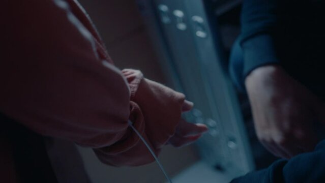 Criminal tying hands of victim with plastic cable tie, going to commit murder or physical violence in dark garage at night. Close-up shot