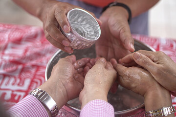 Pour water on the hands of revered elders and ask for blessing. Songkran Day Watering Ceremony.