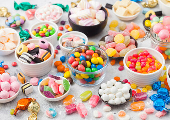 Fototapeta na wymiar Milk chocolate candies woth shell in jar with various jelly gums candies on white background with liquorice allsorts and strawberry bonbons with different sour sugar gums.