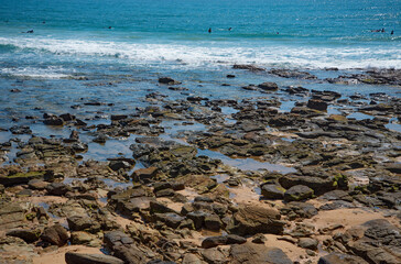 Fototapeta na wymiar Surfers paddling out at Alexandra Headlands with rocks.