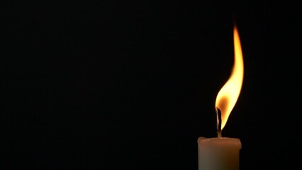Close-up single candle burning on dark black background, candle fire flame light