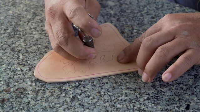 4K, Close-up hand made leather worker, hammersmith's right hand In his left hand, he held iron that was punched make animal skin patterns, craftsman is hammering leather get pattern he wants.