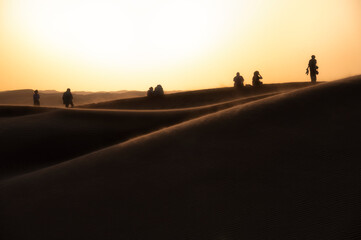 Fototapeta na wymiar Silhouette of people watching sunset on sand dunes of Wahiba Sands
