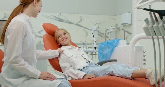 happy smiling child thanking female dentist for successful treatment, doctor and kid are talking having conversation in a dental office. happiness