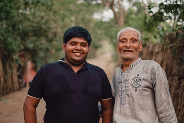 South asian elderly grandfather smiling with his overweight grandson, family happiness concept, togetherness concept, fresh air environment  - obrazy, fototapety, plakaty