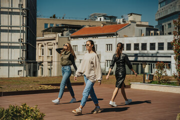 Curly haired girl looking at her phone while walking. Two brunette girls walking and looking somewhere