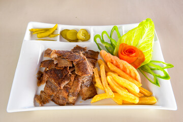 Turkish and Arabic Traditional Ramadan doner kebab with tasty tomato sauce and rice or turkish pilav in white plate on wood table background. ( Pilav ustu doner)