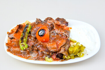 Turkish and Arabic Traditional Ramadan doner kebab with tasty tomato sauce and rice or turkish pilav in white plate on wood table background. ( Pilav ustu doner)