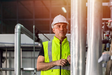 Factory engineer male worker checking high pressure pipe guage in factory boiler room