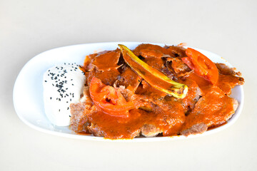 Turkish and Arabic Traditional Ramadan doner kebab with tasty tomato sauce and rice or turkish pilav in white plate on wood table background. ( Pilav ustu doner)