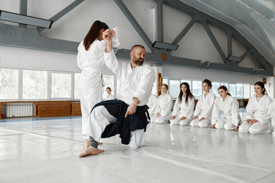Master preparing girls team for sport competition practicing aikido