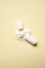 opened capsule showing supplement powder on beige colour background