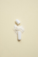 opened capsule showing supplement powder on beige colour background