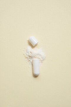 opened capsule showing supplement powder on beige colour background