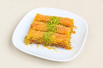 Pistachio kadayif on a plate. Turkish Dessert Kadayif with pistachio powder. Kunefe. Local name burma kadayif