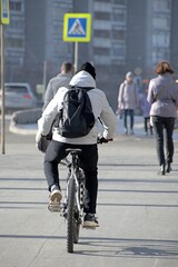 A man rides a bicycle on the sidewalk on a spring morning