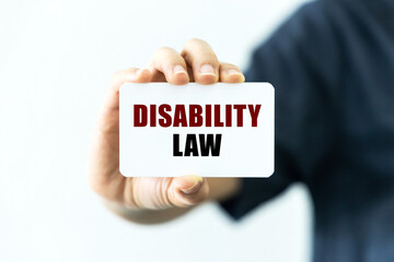Disability law text on blank business card being held by a woman's hand with blurred background. Business concept about disability law.