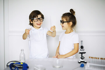 Two cute children at chemistry lesson making experiments on white background