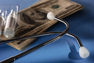 Calculating cost of medical care with stethoscope and ampoules on blue background