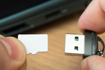 usb flash drive adapter micro sd card connection to laptop. micro sd card in man's hand