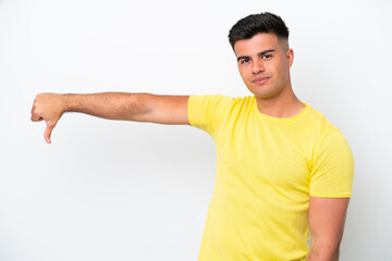 Young caucasian handsome man isolated on white background showing thumb down with negative...