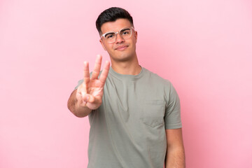 Obraz premium Young caucasian handsome man isolated on pink background happy and counting three with fingers