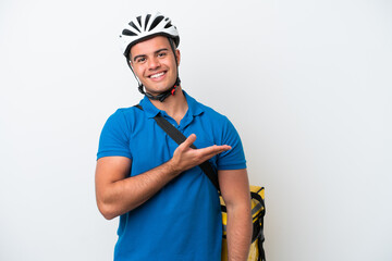 Young caucasian man with thermal backpack isolated on white background presenting an idea while looking smiling towards