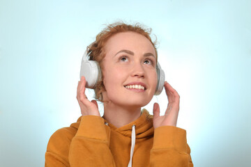 cute redhead curly woman enjoying music in headphones