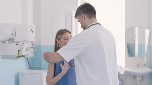 X-ray examination patient in clinic. Doctor giving blue protective wear to patient in front of x-ray .