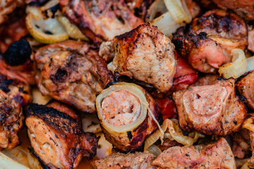Pieces of appetizing fried meat with onions lie on a dish. Grilled meat.