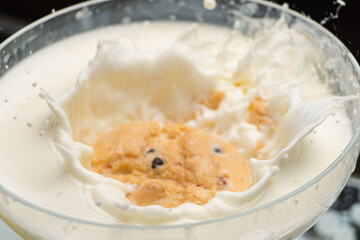 Chocolate Chip Cookie falling and splashing in milk.