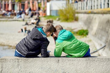 Two teenage boys are playing with phones in the park.