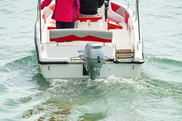 People ride on a pleasure boat. The back of the boat with the motor. 