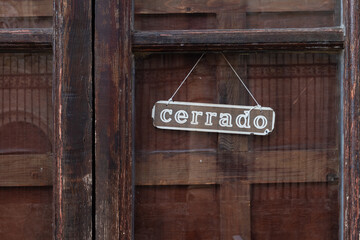 Cartel de cerrado de un negocio colgado de una vieja puerta.