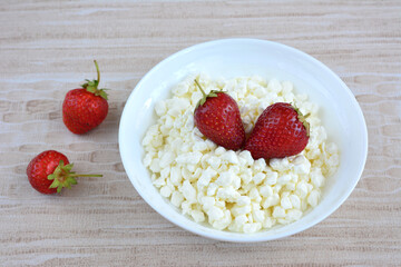 A bowl of cottage cheese with strawberries on top isolated, close-up
