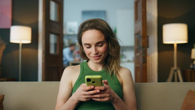 Smiling woman texting telephone living room zoom on. Woman chatting mobile phone