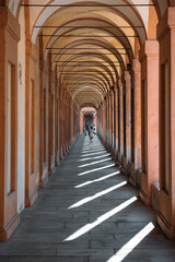 Obraz premium Elegant arches silhouette architectural landmarks in Bologna with happy tourists walking on a sunny warm summer day. The concept of historical heritage. Copyspace