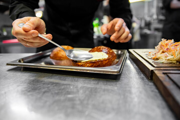 chef hand cooking cheeseburger on restaurant kitchen