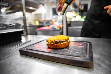 chef hand cooking cheeseburger on restaurant kitchen