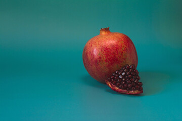 Ripe pomegranate and pomegranate slice close-up on a colored background