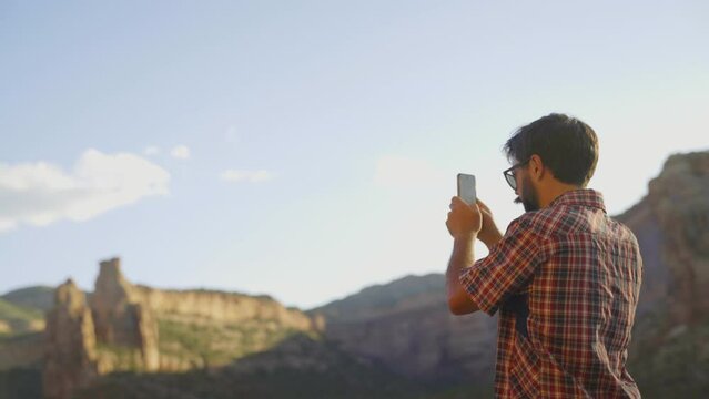 Photographer taking pictures of the beautiful landscape on his smartphone in the USA on a sunny day