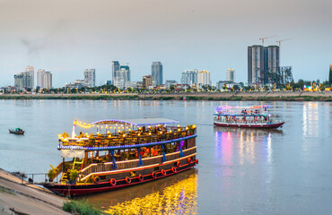 Tourist river cruise boats,lit up at dusk,await customers,Phnom Penh,Cambodia.