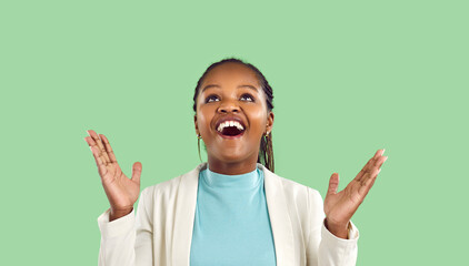Happy dark skinned young woman claps her hands rejoicing in the good news, isolated on light green...